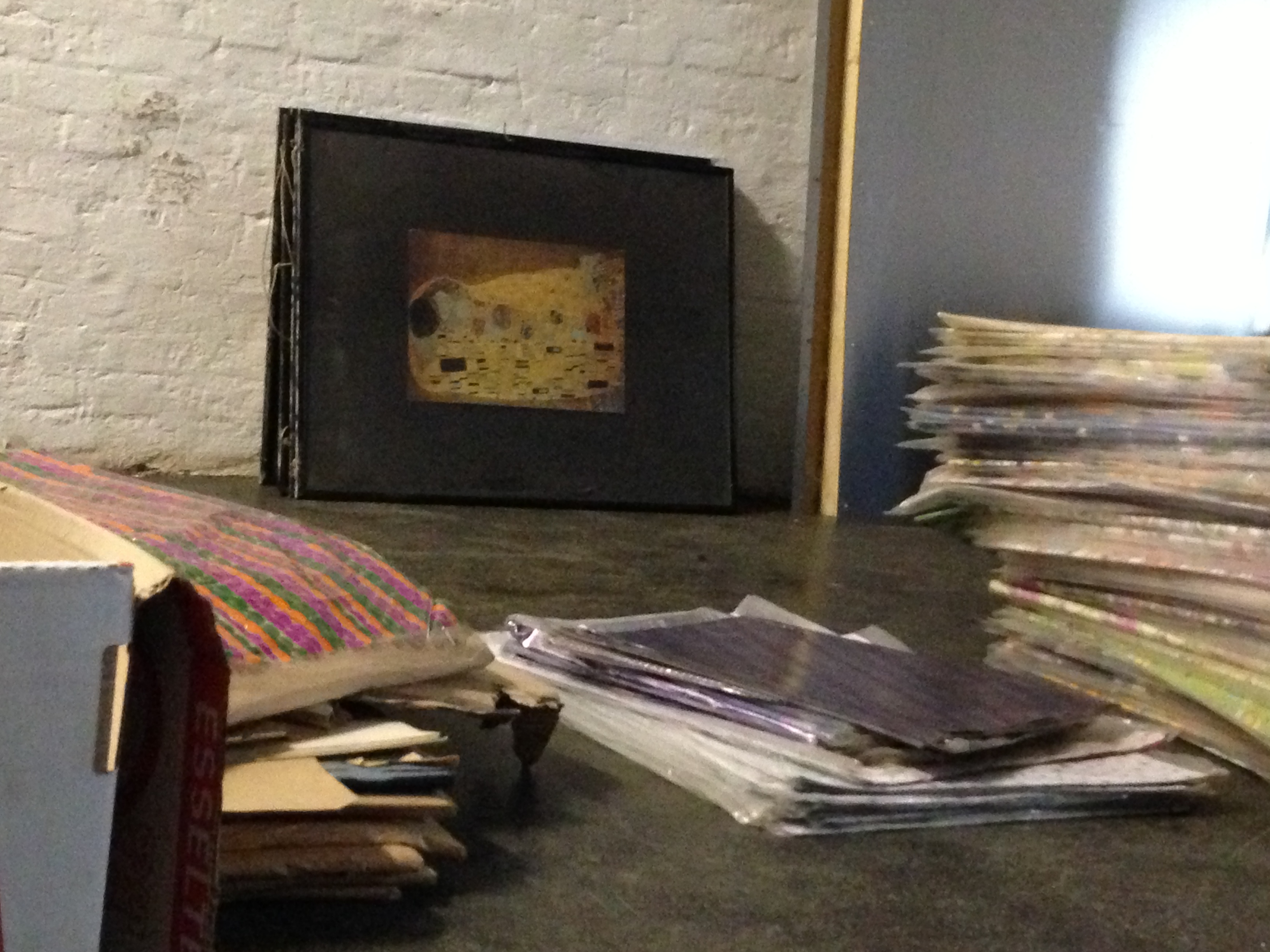 Hinter Papierbögen steht eine Kopie von Gustav Klimts Gemälde „Der Kuss“ verstaubt in einer Ecke.
