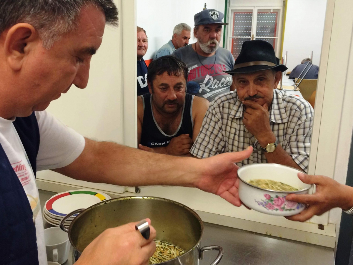 Ein Mann gibt den Obdachlosen Suppe aus. Es gibt in Notschlafstellen mehr Mahlzeiten während Corona.