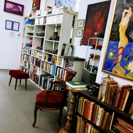 Der Bunte Innenraum des Blauen Ateliers. Bücherregale reihen Bücher aneinander, ein roter Sessel lädt zum Schmöckern ein. 