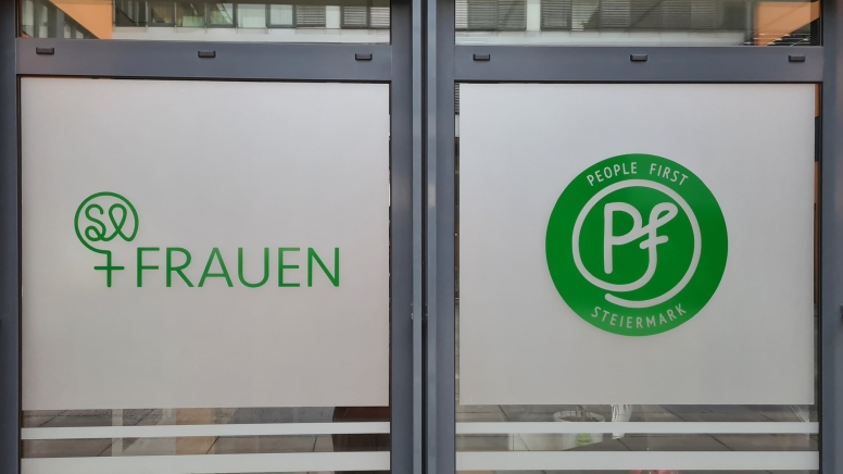 Die Eingangstür vor dem Verein zeigt einerseits das Logo der Frauengruppe und andererseits ihr Motto "people first"