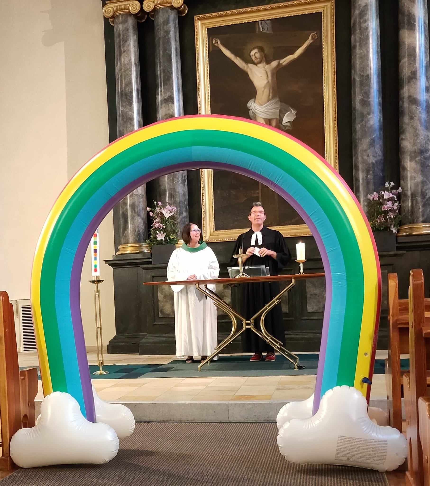 Pfarrer Friedrich Eckhardt predigt symbolisch unter einem Regenbogen.