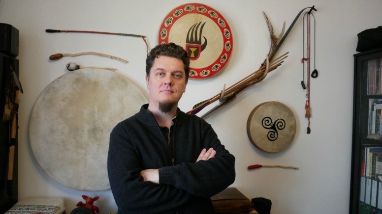 Bernhard Reicher vor einer Wand mit Artefakten