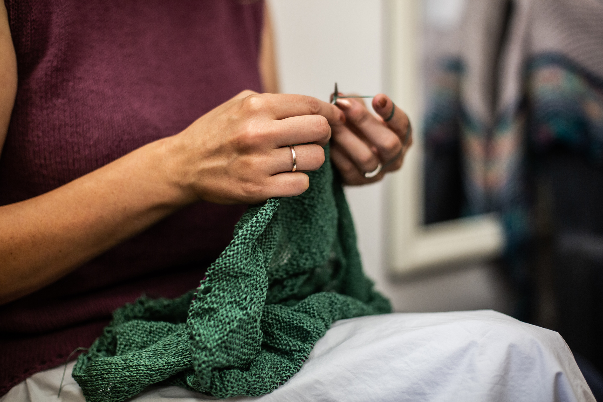Eine Dame strickt einen grünen Pullover.