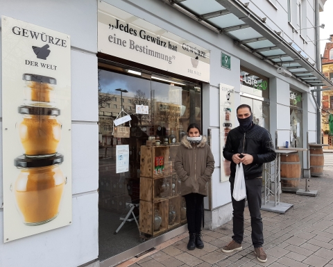 Hassan und Judy stehen vor der Glastür der "Welt der Gewürze".