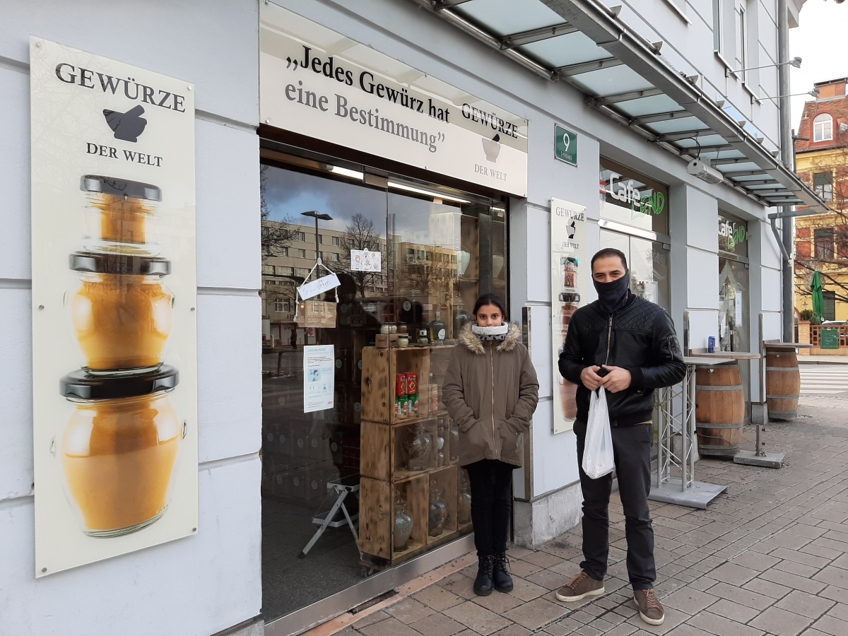 Hassan und Judy stehen vor der Glastür der "Welt der Gewürze".