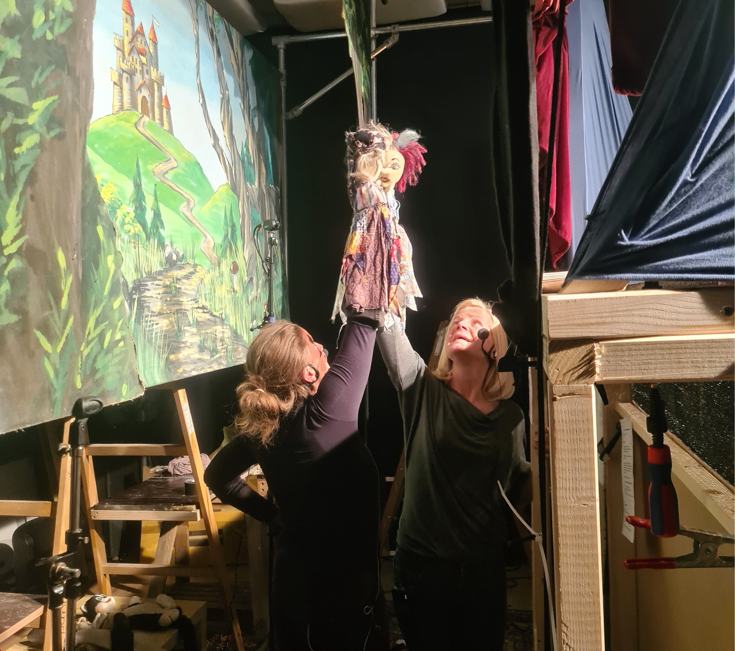 Zwei Schauspielerinnen spielen über ihren Köpfen mit den Handpuppen von Kasperl.