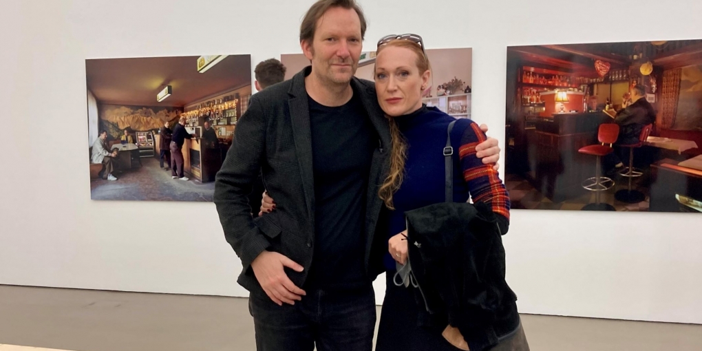 links ist Rainer Frimmel zu sehen, rechts Tizza Covi. Sie befinden sich im Ausstellungsraum der Camera Austria, im Hintergrund sieht man Bilder aus Wien.