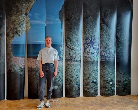 Künstlerin Lisa Hopf vor ihrer Installation "Kyras Paradise". Im Hintergrund erkennt man das Foto einer Höhle.