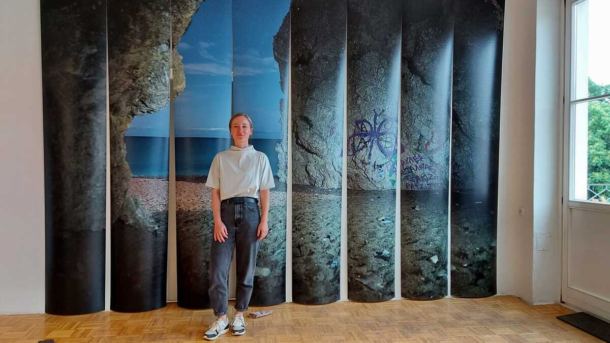 Künstlerin Lisa Hopf vor ihrer Installation "Kyras Paradise". Im Hintergrund erkennt man das Foto einer Höhle.