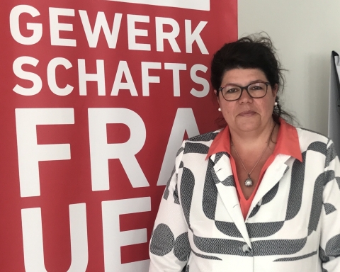 Helga Ahrer steht vor einem roten Banner mit der Aufschrift „Gewerkschaftsfrauen".