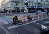 Drei Klimaaktivist:innen sitzen auf der Straße und halten Banner mit ihren Forderungen.