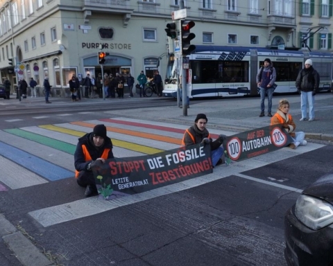 Drei Klimaaktivist:innen sitzen auf der Straße und halten Banner mit ihren Forderungen.