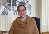 Eine Frau mittleren Alters steht hinter der Rezeption und lächelt in die Kamera