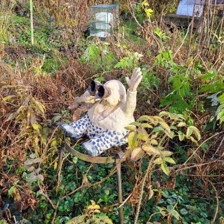 Skulptur eines Männchen mit einem Fernrohr, der im Garten sitzt