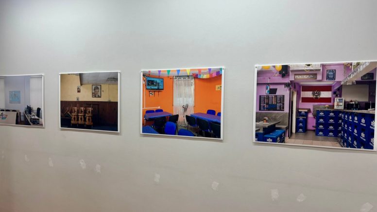 An der Wand hängen Bilder von österreichischen Beisln, einem bunten Lokal und das Büro des Migrant:innenbeirats.
