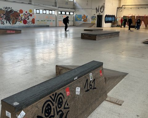Die neue Skaterhalle. Ein mit Graffiti besprühtes Hindernis steht im Vordergrund. Im Hintergrund ist klein noch eine Person von hinten zu sehen.