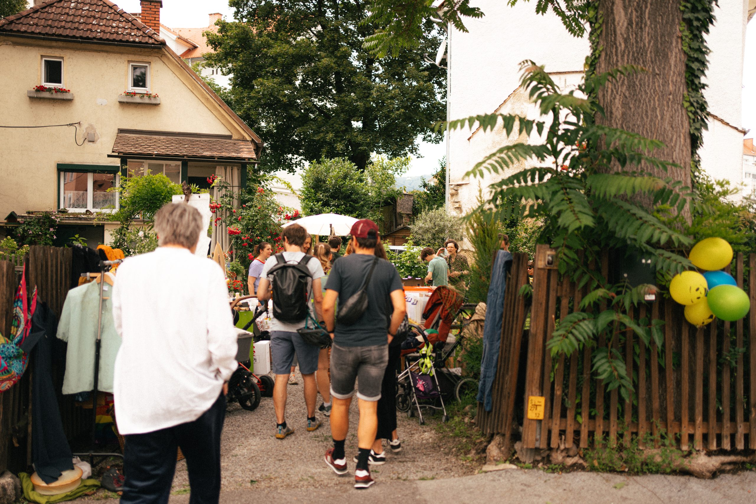 Menschen beim Eingang eines Gartens, am Weg zu den Verkaufsständen.