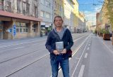 Der Autor Heimo Halbrainer steht in der Annenstraße und hält das Buch in der Hand.