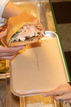 Es ist ein verchromtes Tablett mit einer Auflage die den Aufrduck "LOOP Kebab" trägt zu sehen. Der fertige Döner wird aufs Tablett gelegt.