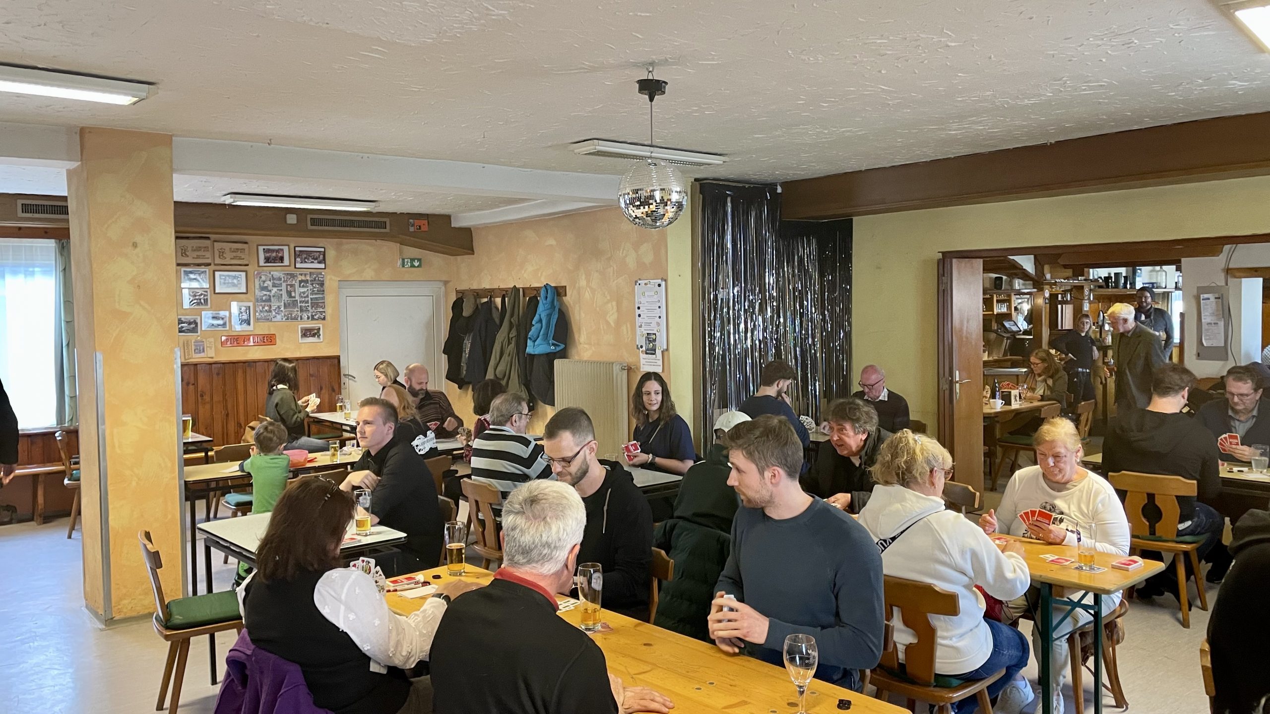 Gäste des Schnapsturniers sitzen im Gasthaus Fasching an den Tischen und spielen Karten