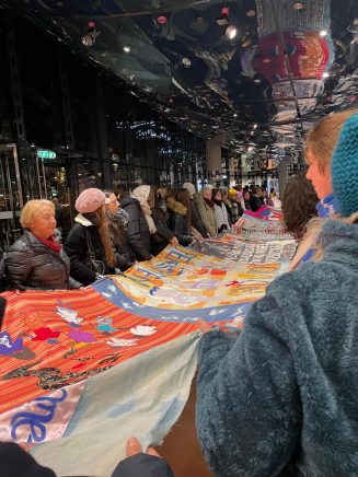 Gemeinschaftlich wird ein selbtsgemachtes Banner in die Luft gehalten