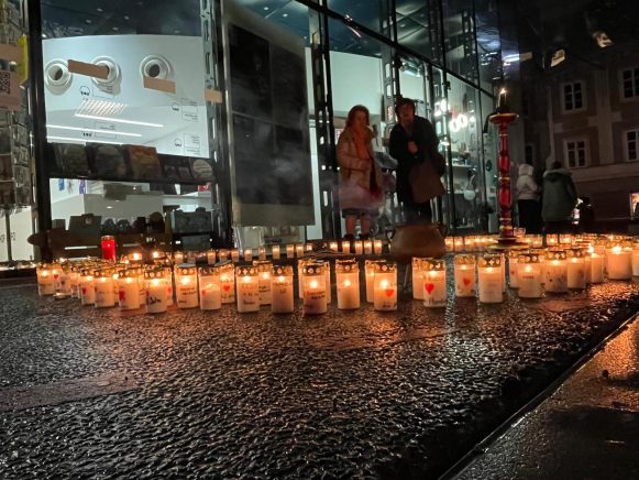 Auf dem Foo befindet sich ein Kreis aus Kerzen. Auf jeder Kerze steht Name und Alter eines Opfers von Femizid in den ltzten 5 Jahren