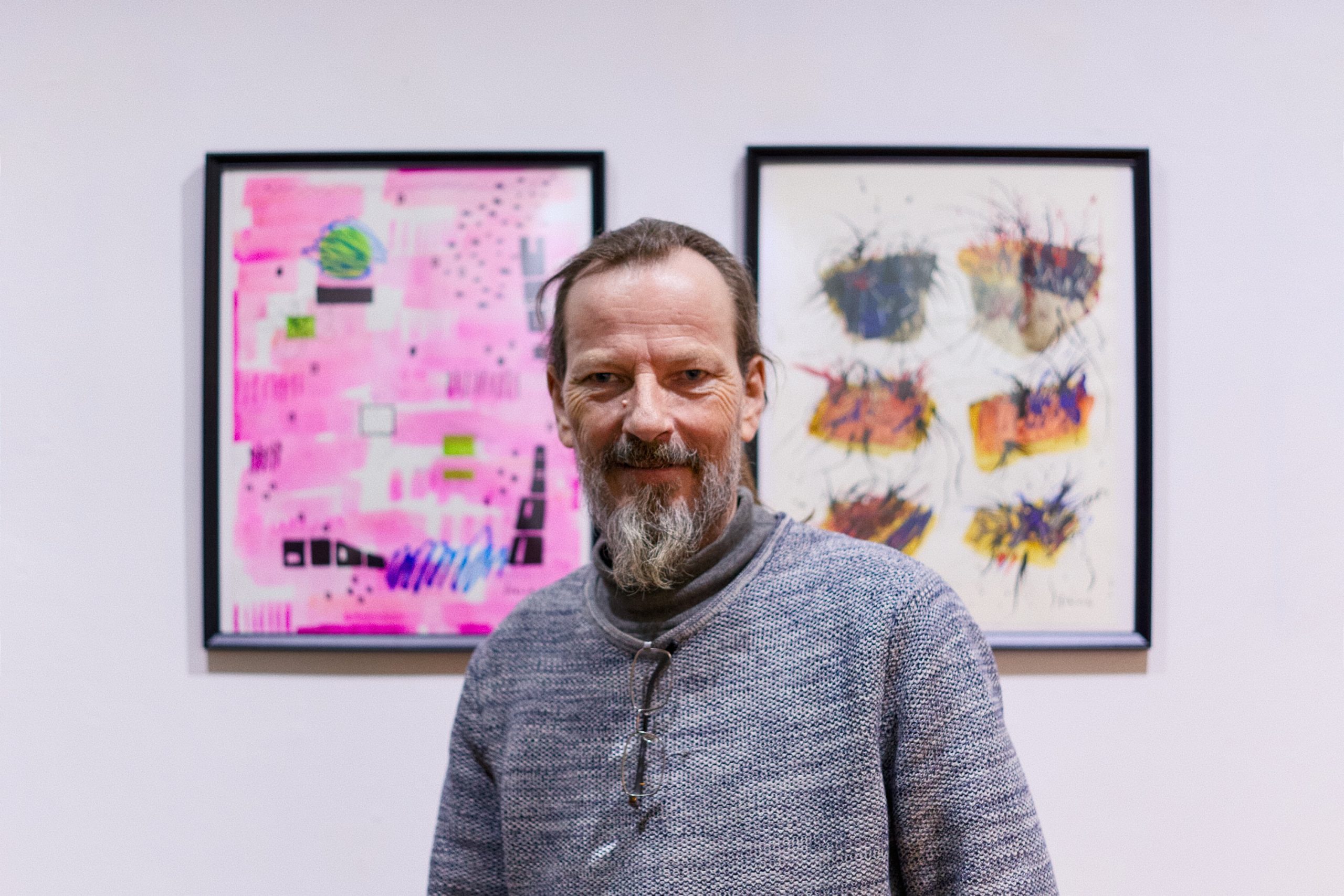 Der Künstler Jakob Böhme steht vor 2 Gemälden.