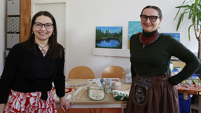 Galyna Skotnik und Mariia Mitić vom ukrainischen Kulturverein Ridna Domivka stehen vor einem Tisch mit handgefertigten Produkten wie buntem Schmuck, einer traditionellen Tasche und Keramik