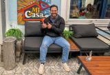 Mario Rosales Bados lächelnd auf einer Sitzgarnitur vor seinem Lokal Mi Casa