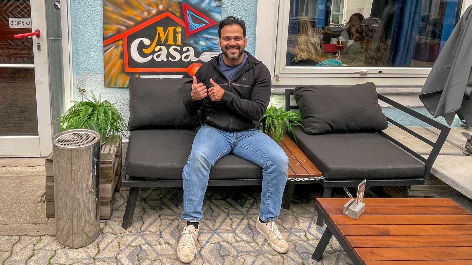 Mario Rosales Bados lächelnd auf einer Sitzgarnitur vor seinem Lokal Mi Casa