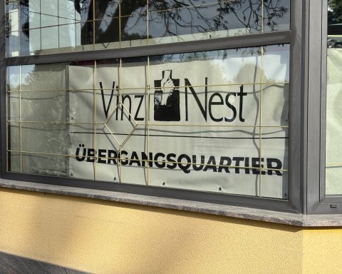 Im Fenster des Übergangsquartiers hängt ein Plakat mit der Aufschrift VinziNest.