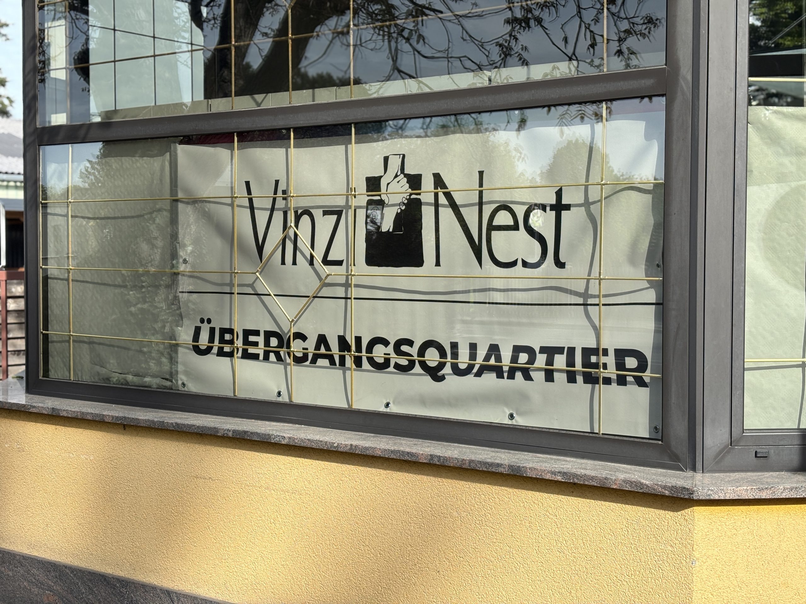 Im Fenster des Übergangsquartiers hängt ein Plakat mit der Aufschrift VinziNest.