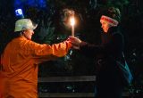 Zwei Personen in dunkler Umgebung. Sie haben eine brennende Fackel in der Hand.